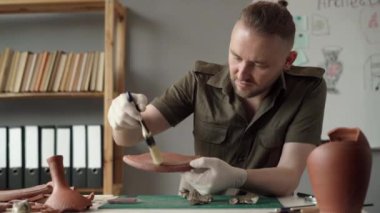 Ofiste çalışan bir arkeolog, eski bir kil eserini inceliyor. Arkeolojik çalışma. Boşluğu kopyala