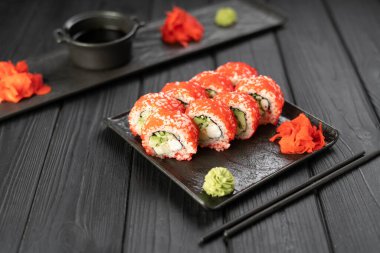 Suşi seti, havyar, avokado ve somon siyah tahta tabakta. Asya mutfağı konsepti. Boşluğu kopyala