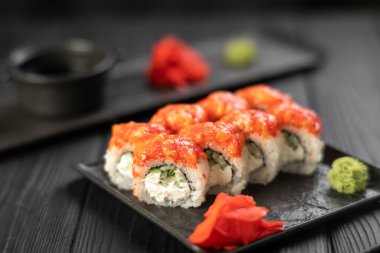 Suşi, somon, havyar, salatalık ve krem peynirli siyah bir tabakta. Japon yemeği. Suşi menüsü kavramı. Boşluğu kopyala