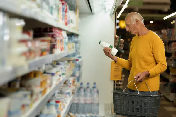 An elderly man buying dairy products in a store or supermarket. Copy space