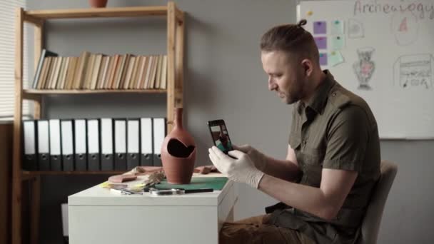 Bütün Gün Ofiste Çalışan Erkek Arkeolog Masasında Otururken Telefonla Fotoğraf — Stok video