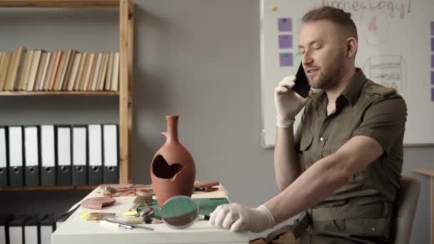 Mužský Archeolog Pracující Kanceláři Studující Starověké Artefakty Volající Kolegy Zatímco — Stock video