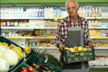 Markette elma sandığı taşıyan yaşlı erkek işçinin portresi. Boşluğu kopyala