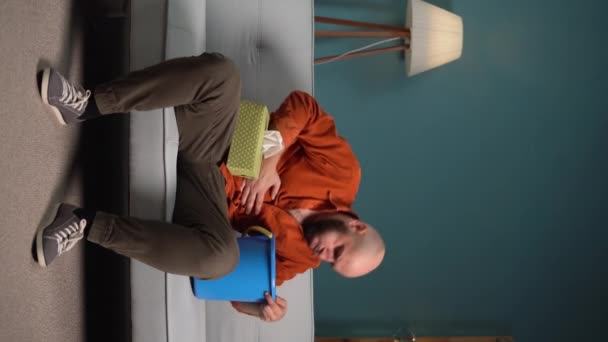 吐き気や嘔吐に苦しむ男性が自宅のソファーに座っています バーティカルビデオ — ストック動画
