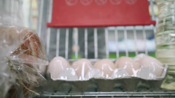 スーパーマーケットを歩くカートを持つ女性は 店で食料品を購入し 野菜部門にトマトを入れる クローズアップ — ストック動画