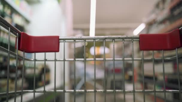 Kupujący Spacerujący Przejściu Supermarketu Pustym Wózkiem Wkładający Niego Dwie Butelki — Wideo stockowe
