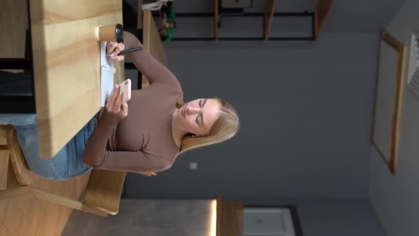 Kapalı Kafedeki Güzel Sarışın Kadın Defterine Tutarken Cep Telefonu Kullanıyor — Stok video