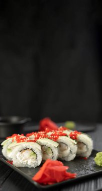 Sebzeli lezzetli suşi, siyah ahşap arka planda bir tabakta servis ediliyor. Japon yemeği konsepti. Dikey pankart