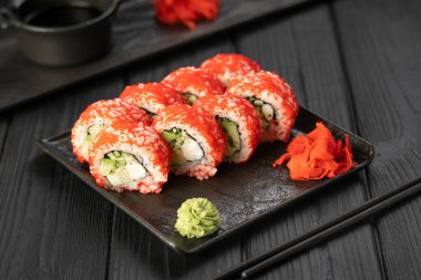 Büyük suşi ruloları, siyah taş tabakta balık ve havyar. Japon mutfağı kavramı