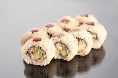 Suşi rulo krem peynirli ve füme yılan balıklı beyaz arka planda yansımalı. Boşluğu kopyala