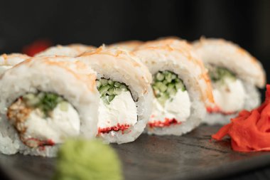 Lokantada siyah bir tabakta servis edilen karidesli suşi rulolarının yakın çekimi. Suşi menüsü kavramı