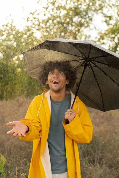 Schöner Arabischer Mann Mit Regenschirm Während Draußen Spaziert Blickt Mit — Stockfoto