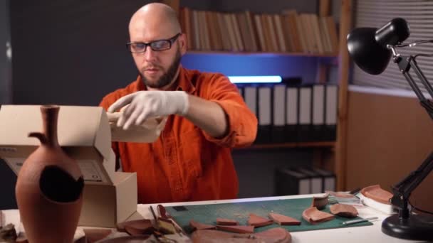 Samiec Archeologa Pracujący Biurze Późną Nocą Pakuje Pudełko Zabytkowym Wazonem — Wideo stockowe