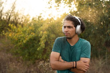 Soğuk yağmur altında, kulaklık takan huysuz Arap adam yağmurlu havadan nefret eder. Boşluğu kopyala