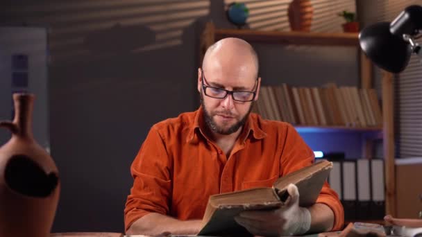 Археолог Читающий Старую Книгу Работающую Офисе Поздно Ночью Изучая Информацию — стоковое видео