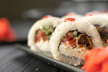 Siyah arka planda yılan balığı ve susam tohumlarıyla hazırlanmış suşi, yakın plan. Boşluğu kopyala