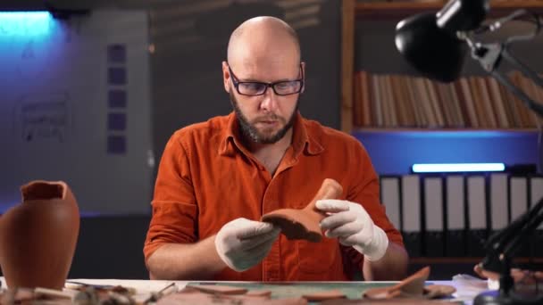 Łysy Archeolog Pracujący Biurze Późną Nocą Analizuje Starożytny Artefakt Patrząc — Wideo stockowe