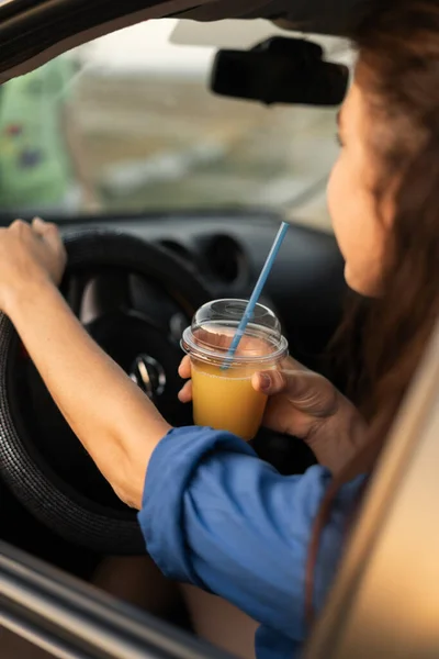 Όμορφη Γυναίκα Οδηγεί Ένα Αυτοκίνητο Και Πίνει Χυμό Πορτοκάλι Ενώ — Φωτογραφία Αρχείου