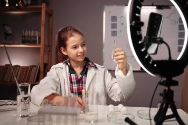 İlginç bir deney. Genç ve zeki bir kız video blogu kaydediyor ve kimyasalları doğru karıştırmayı gösteriyor, kimya deneyi yapıyor. Uzaklık eğitimi, okul ve video bloglama kavramı
