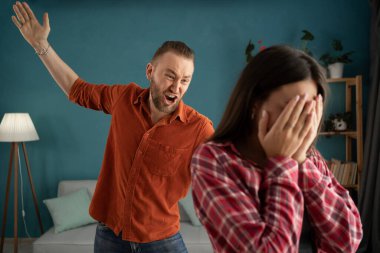 Aile içi şiddet korkusu. Tacizci koca, ağlayan karısını dövmekle tehdit etti. Saldırgan erkekten saklanan korkmuş savunmasız kadın kurbanı. Boşluğu kopyala