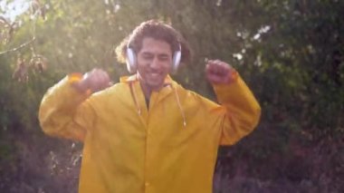 Genç Arap adam yağmurda dans ediyor kulaklıkla müzik dinliyor yaz yağmurlu havanın tadını çıkarıyor. Boşluğu kopyala