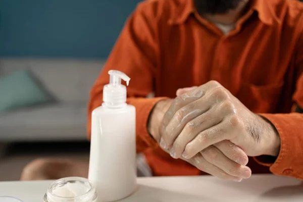 Close-up of a man applying moisturizer to his hands. Taking care of a man\'s body. Copy space