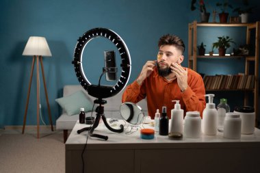 Erkek güzellik blogcusu, iç mekandaki sosyal medyada günlük cilt bakımı rutin değerlendirmelerini kaydeden göz altına güzellik yamaları uyguluyor. Yayın kavramı