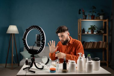 Sakallı adam blogcusu kozmetik ürünlerini nasıl kullanacağını gösteriyor. İş dünyası sosyal medya kavramını etkiliyor. Boşluğu kopyala