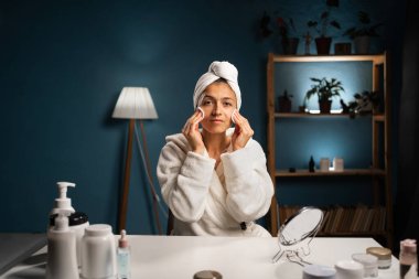 Beyaz bloknotu olan bir kadın. Kozmetik pedlerle yüz derisinden makyaj yapan kadın. Yüz bakımı konsepti