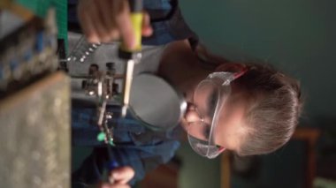Evde lehim aleti olan genç bir kız. Bilgisayar donanım mühendisliği, teknoloji ve bilim konsepti onarılıyor. Dikey video