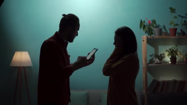 丈夫和妻子在墙边辩论的轮廓 一个男人指控他的女朋友通奸 并在智能手机屏幕上显示她的情人的留言 复制空间 — 图库视频影像