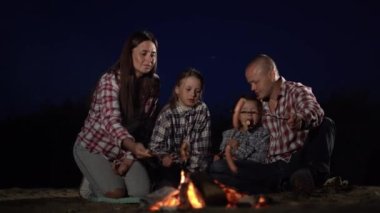 Aile kampı ve kamp ateşinde sosis pişirme gece yarısı göl kenarında. Boşluğu kopyala