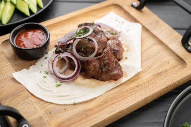 Pita ekmeğinde soğanlı domuz eti parçaları. Ahşap tahtada sos ile servis yap. Boşluğu kopyala