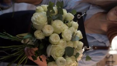 Kadın çiçekçi çiçekçide beyaz güllerden güzel bir buket yapıyor. Dikey video.