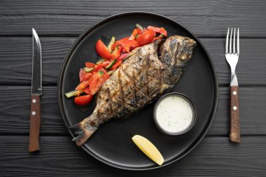 Koyu ahşap arka planda garnitürlü ızgara dorado, üst manzara. BBC balığı ve sebzeli kompozisyon. Kızarmış dorado. Balık yemeği..