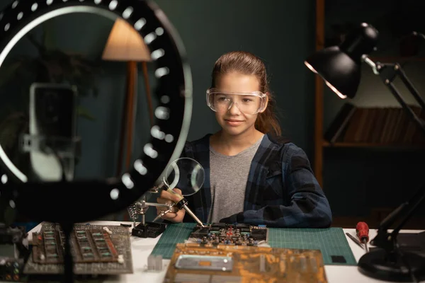child live-streaming diy computer repair, tech-savvy kid takes on motherboard repair in livestream, young blogger\'s electronics journey: soldering skills and social media share. Copy space