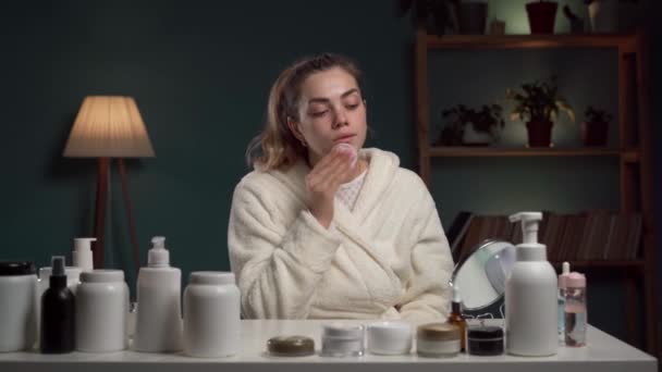 白いバスローブの美しい女性は 睡眠のために準備する綿パッドで顔にトナーまたはミクラー水を置きます スキンケアのコンセプト コピースペース — ストック動画