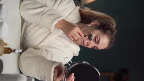 Młoda Kobieta Używająca Nefrytowego Wałka Masażu Twarzy Domu Pionowe Wideo — Wideo stockowe