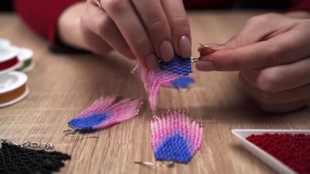 創造性と趣味のコンセプト 三角ビーズのイヤリングを作る女性 クローズアップ 針仕事およびビードのためのビーズ コピースペース — ストック動画