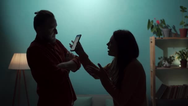 嫉妬の概念 若いカップル 女性は嫉妬し 夫からスマートフォンを奪い 説明を要求します コピースペース — ストック動画