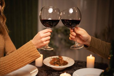 Romantik yemek konsepti. Sevgililer Günü 'nü kutluyoruz. Çiftin elleri restoranda buluşan kırmızı şarap kadehlerini tokuşturuyor. Boşluğu kopyala
