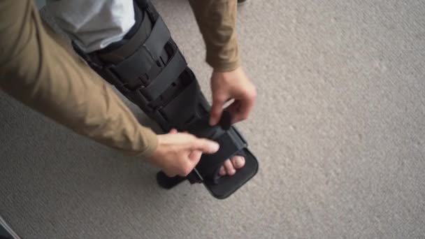 Fiatal Férfi Lábsérüléssel Sínen Lépegető Bakancsban Orthosisban Kificamodott Bokával Otthon — Stock videók