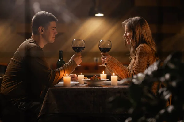 透过粗糙的窗户 可以看到年轻夫妇热恋饮酒 在家中庆祝情人节 与蜡烛共进浪漫的晚餐 复制空间 图库照片