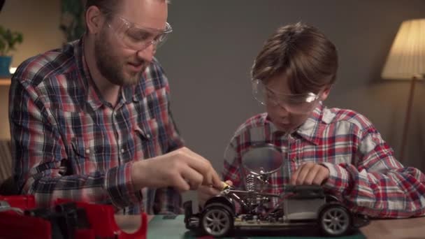 Vader Zoon Repareren Een Speelgoedauto Met Een Soldeerbout Thuis Kopieerruimte — Stockvideo