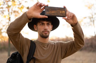 Açık havada macera tatili. Sırt çantalı ve telefonlu bir fotoğrafçı sonbahar ormanının fotoğrafını çekiyor. Seyahat yaşam tarzı ve hobi konsepti. Boşluğu kopyala