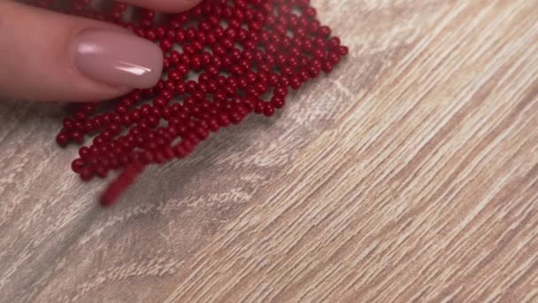 Женщина Создает Браслет Ручной Работы Используя Красные Бусины Сидя Столом — стоковое видео