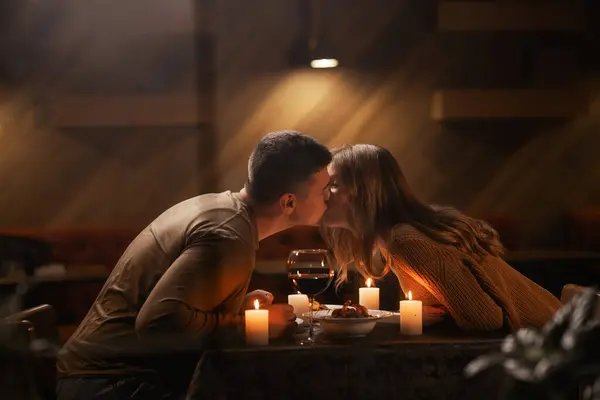 恋爱中快乐的年轻夫妇亲吻着 喝着红酒吃着浪漫的晚餐 庆祝情人节 结婚周年纪念日 坐在家里 复制空间 免版税图库图片
