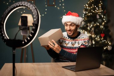 Sosyal medya teknolojisi etkileyicisi Noel 'de evde boks videosu açıyor. Noel indirimi, online alışveriş. Boşluğu kopyala