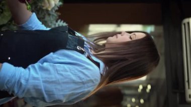 Çiçekçi, çiçekçide farklı çiçeklerden modern buket yapıyor. Dikey video