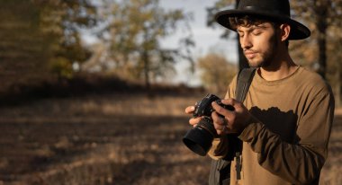 Doğa fotoğrafçısı. DSR kameralı Arap adam sonbahar ormanında doğayı çekiyor. Pankart. Boşluğu kopyala